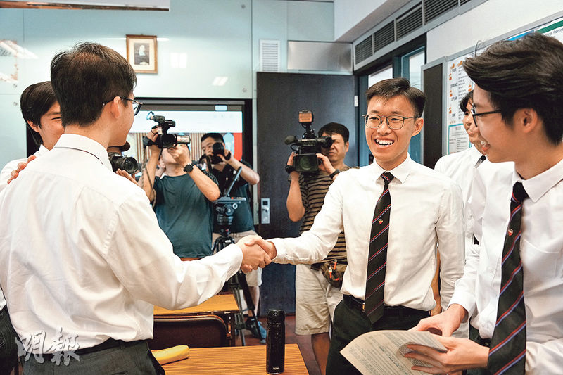 喇沙書院「超級狀元」陳博軒（右二）盼留港讀醫，昨日領取成績通知書時，不少同學上前道賀。（賴俊傑攝）