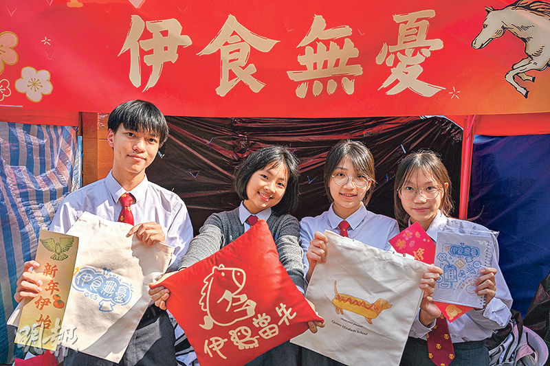伊利沙伯中學的學生今年以「伊食無憂」為主題在維園年宵市場擺檔。萬同學（右一）表示，同學特別設計將校名的「伊」字融入產品，包括「伊馬當先」攬枕。（盧曼盈攝）