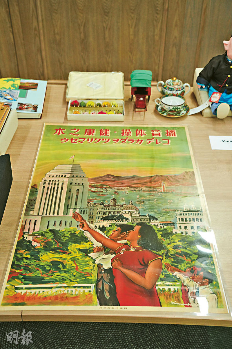 健康之本海報：由日東印刷所於1942至1945年香港日佔時期印製，海報展示當年維港景觀，當中有一對男女指向遠處的建築，實為第三代匯豐總行大廈，配以「播音体操 健康之本」字句，以宣傳廣播體操的重要，促進市民健康。（黃志東攝）