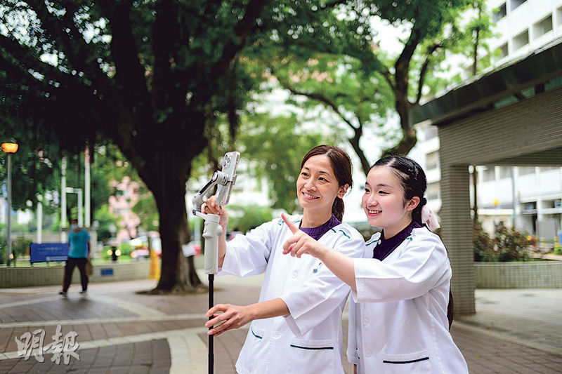 伊利沙伯醫院職業治療部資深職業治療師楊寶璇(左)及駐院職業治療師賴曉慧(右)於公餘時間自發到不同地方,為晚期病人拍攝照片並製成VR片,讓他們「重遊舊地」。兩人受訪時示範在大樹下以手機、自拍棍等器材拍攝360度相片,再剪輯成可於VR眼鏡使用的片段。(鄧宗弘攝)