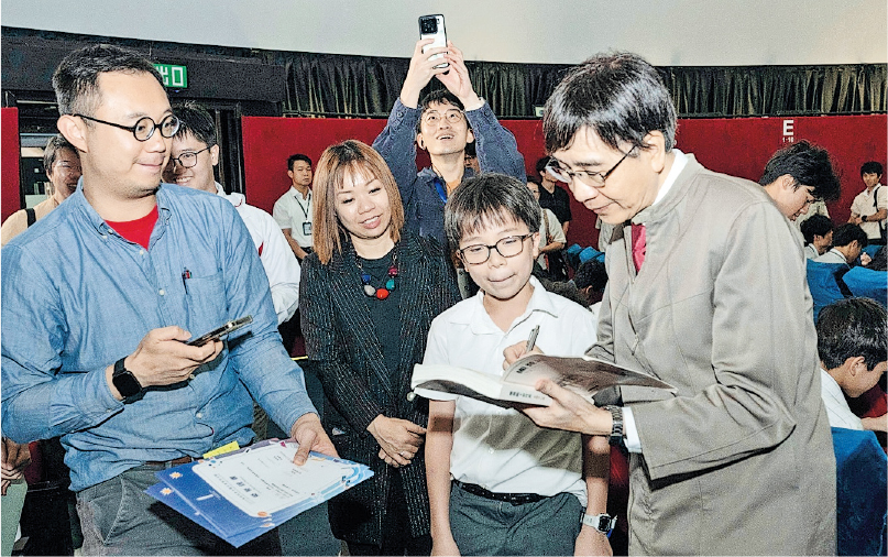 港大醫學院微生物學系講座教授袁國勇（前右）於周二在香港太空館出席「Hello Scientists 你好科學家」講座，與逾200名中學生跨世代對談。有學生在講座後拿着袁國勇出版的自傳索取簽名。（未來科學大獎基金會提供） 
